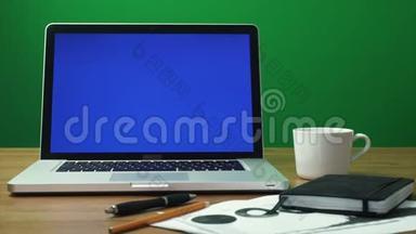 笔记本电脑，桌面上有绿色屏幕和黑色记事本。 绿色屏幕背景